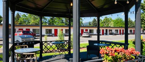 A covered outdoor seating area with tables and chairs, a barbecue grill, and a sign indicating it's for guests only.