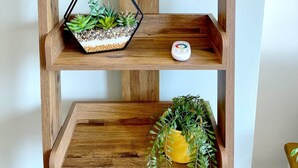 A wooden shelf unit with a decorative lamp, a hexagonal planter with succulents, and a small white object on the middle shelf. - Stylish Apartment with views, lift and parking (Scarborough)