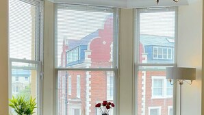 A room with large windows, a round table with chairs, a potted plant, and a blue sofa. - Stylish Apartment with views, lift and parking (Scarborough)
