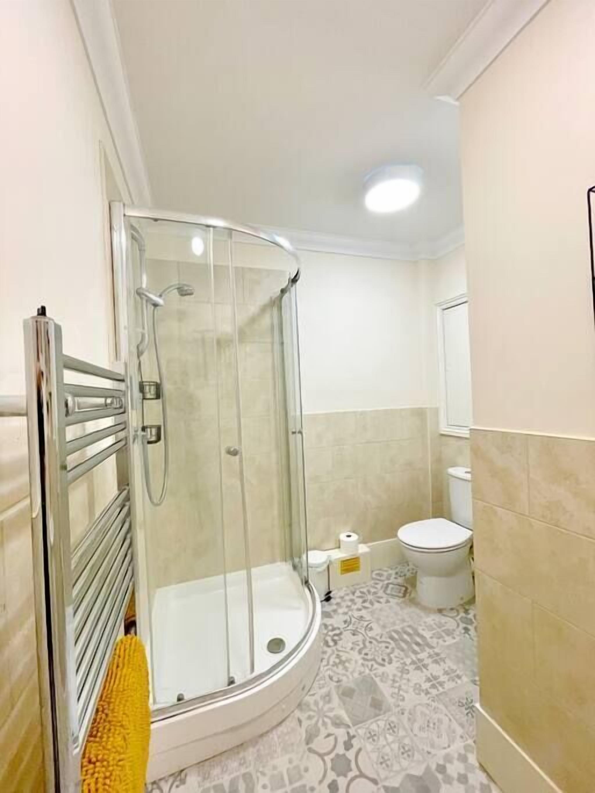 Un baño con ducha separada por mamparas de vidrio, inodoro y lavamanos.