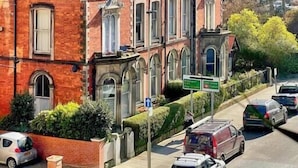 Un immeuble de plusieurs étages, construit en briques rouges, qui présente un style architectural classique, avec des fenêtres en arc et une entrée imposante.