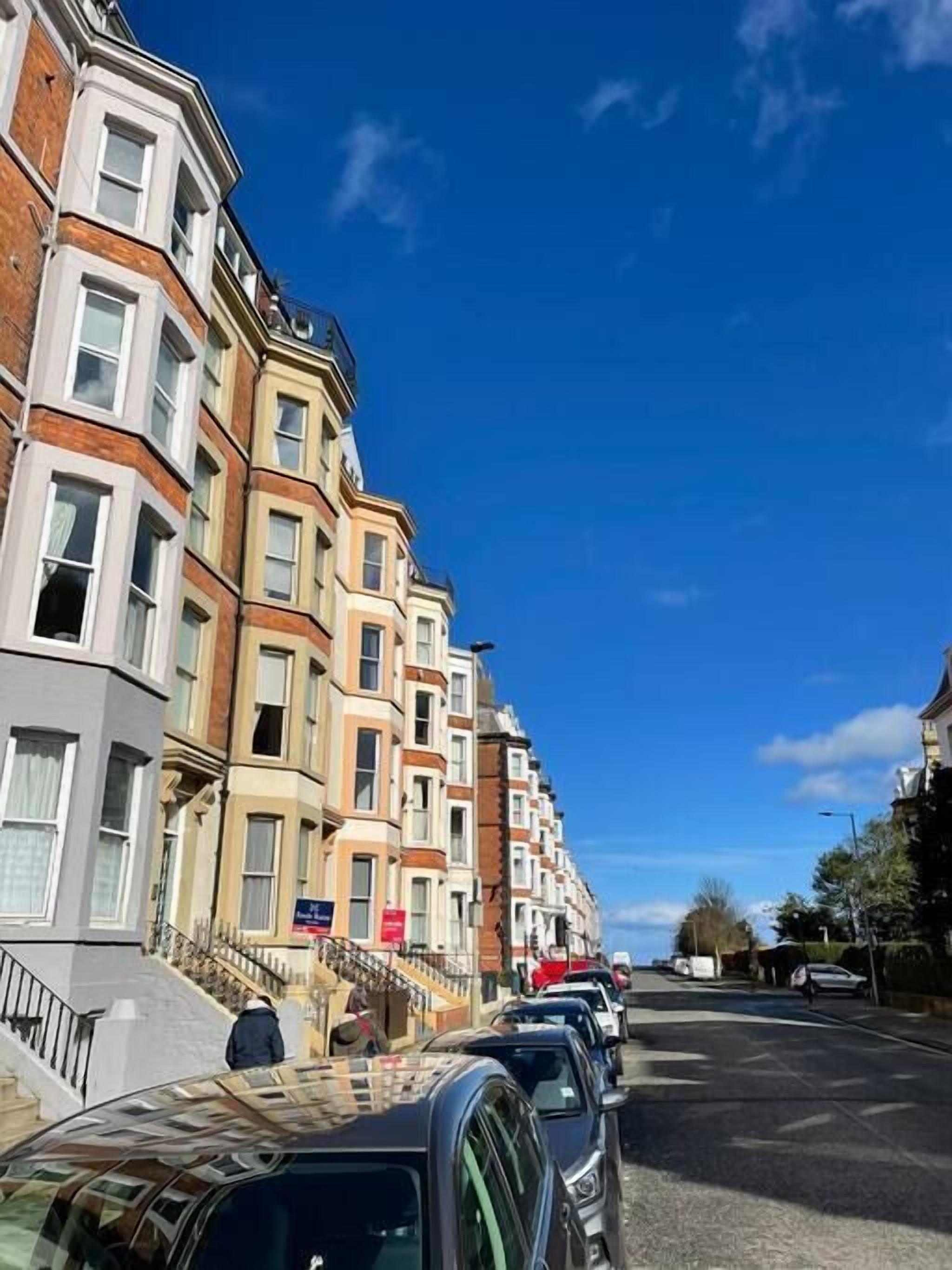 A row of multi-story buildings with bay windows and a clear blue sky.
