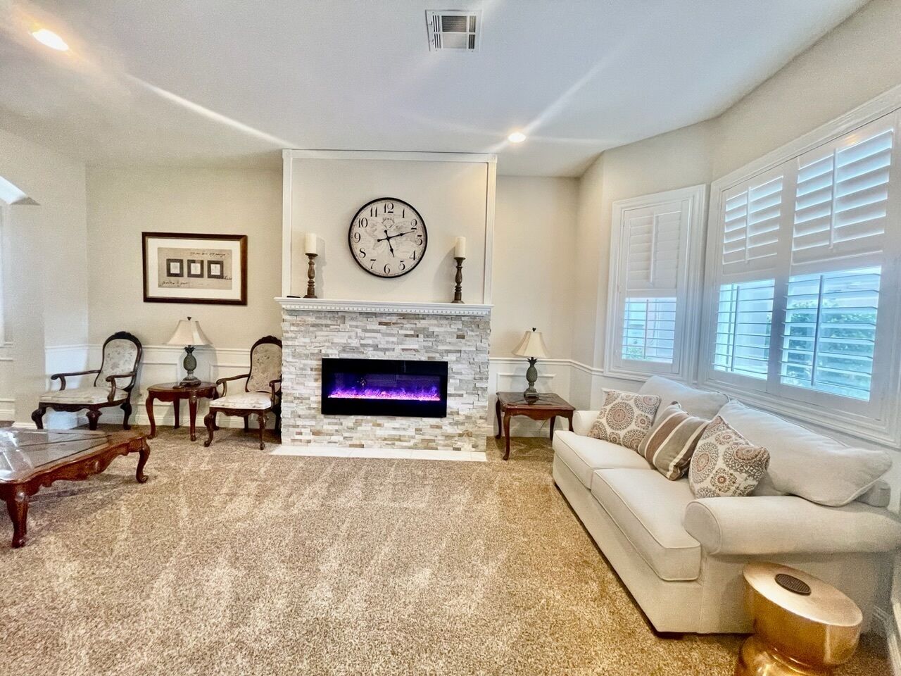 A living room with a fireplace, a clock, and a sofa.