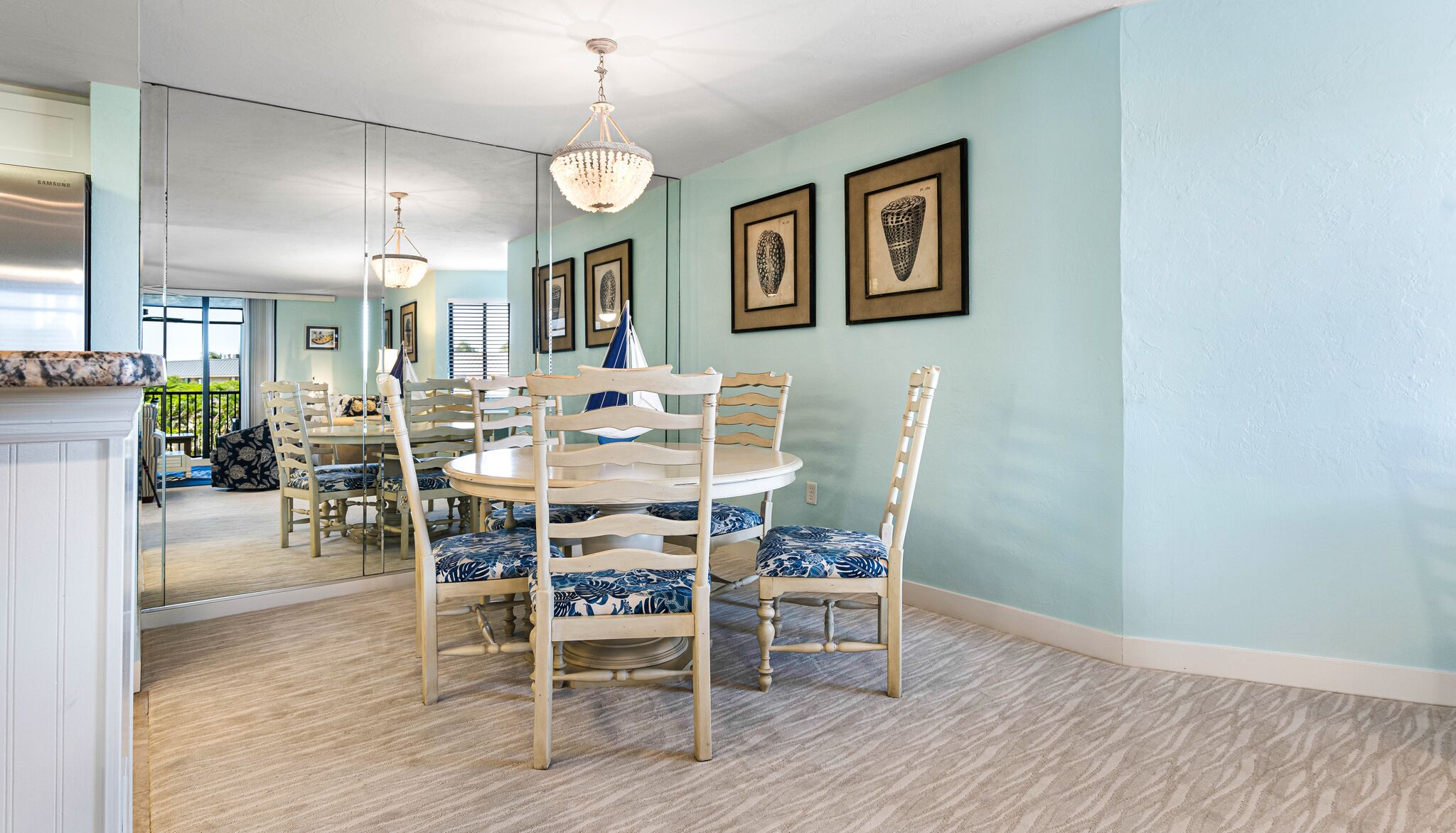 A dining area with a round table, chairs, and a chandelier.