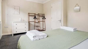 Una camera da letto con un letto, una cassettiera, uno specchio e un appendiabiti.