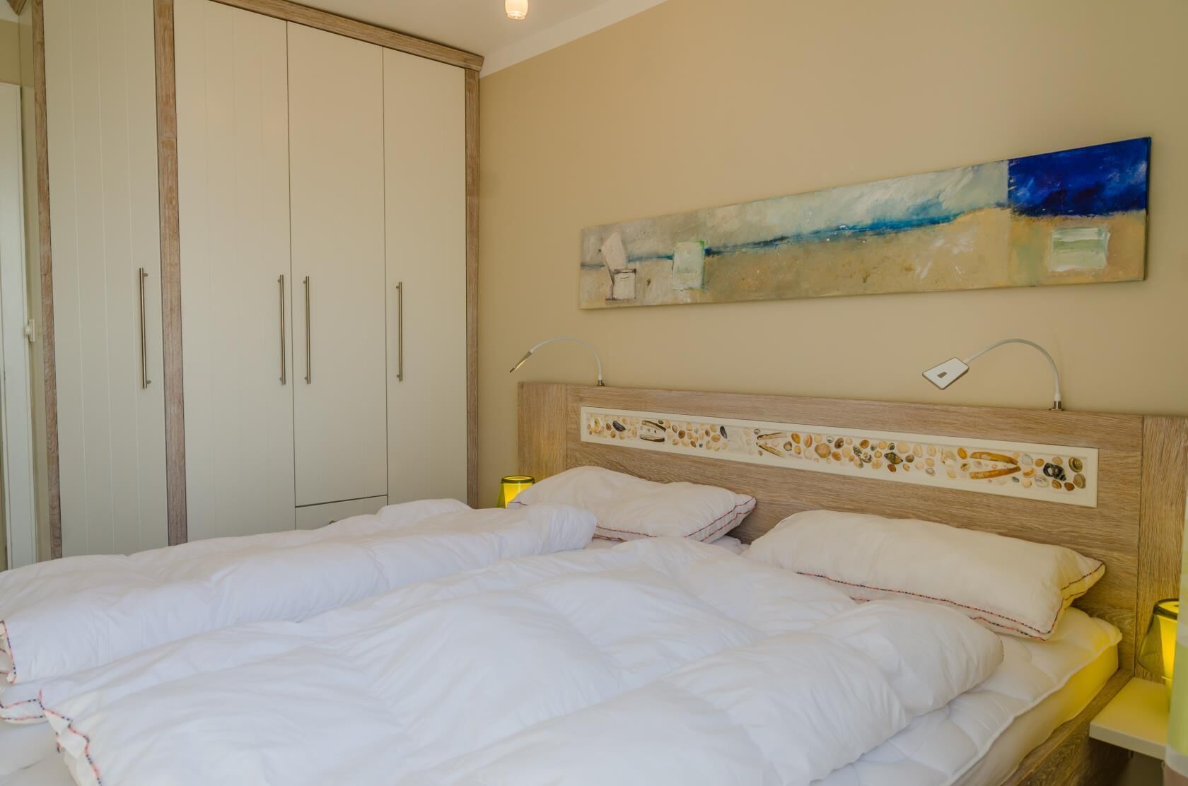 Een slaapkamer met een groot bed, een houten hoofdbord met decoratieve details, een schilderij boven het bed en een inloopkast.