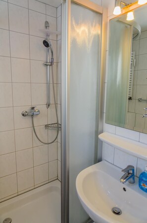 Ein Badezimmer mit Dusche, Waschbecken und Spiegel.