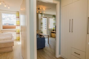 Ein modernes Apartment mit Holzboden, einem Bett, einer Essecke und einer Küche.