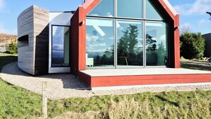 Ein modernes Haus mit einem großen Glasfenster, einem Schornstein und einem roten Dach.