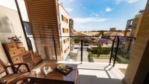 Un balcone con un tavolo di legno, sedie e vista su una zona residenziale.