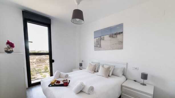 Una camera da letto con un letto, comodini, una finestra vista e un quadro appeso al muro.