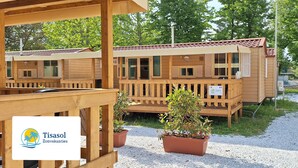 A row of wooden cabins with a covered porch and potted plants in front.