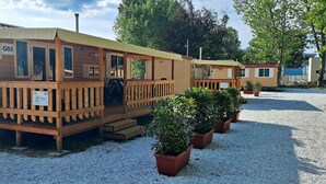 A row of wooden cabins with a deck, labeled G03, and potted plants in front.