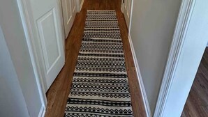 A hallway with white doors, a patterned rug, and decorative wall art.