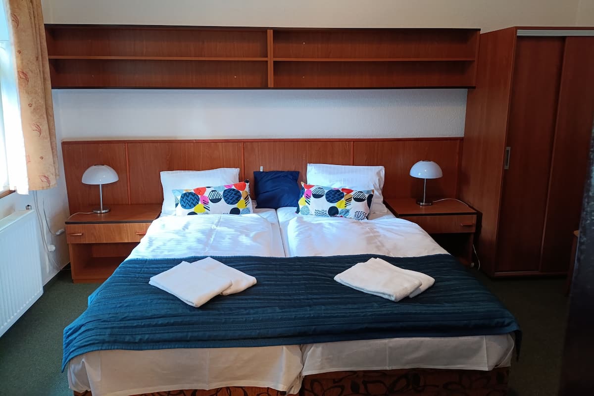 Una cama bien hecha con un edredón azul, dos almohadas con diseños coloridos y dos lámparas de noche.