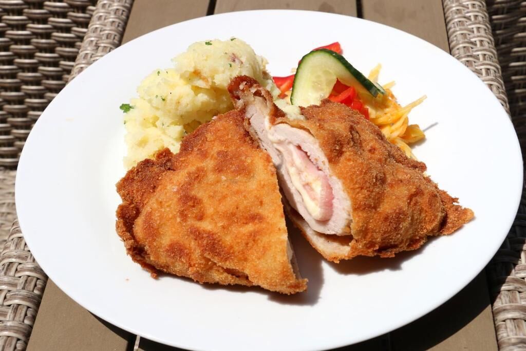 Un plato con una milanesa empanizada y frita, puré de papas y una ensalada.