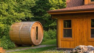 A wooden sauna barrel and a cabin with a sloped roof.