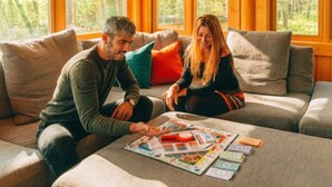 Dos personas sentadas en un sofá con un juego de mesa delante.