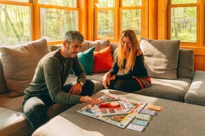 Zwei Personen sitzen auf einer Couch mit einem Gesellschaftsspiel davor.