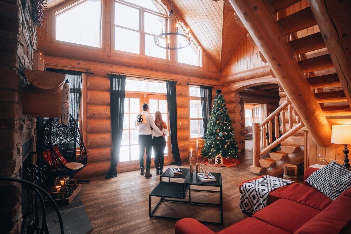 Interior de cabana de madeira com escada, árvore de Natal, sofá e mesa de centro.