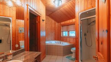A wooden cabin bathroom with a bathtub, shower, and a sink.