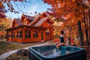 A log cabin with a hot tub in the yard.