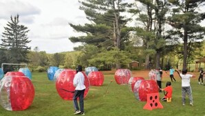 Un espacio para actividades al aire libre donde personas juegan con pelotas grandes, transparentes y opacas.