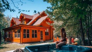 Una cabaña de troncos con un jacuzzi al frente.