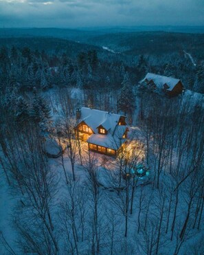 Een sneeuwlandschap met een groot huis, omringd door bomen.