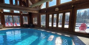 Une piscine intérieure avec des murs en bois et de grandes fenêtres.