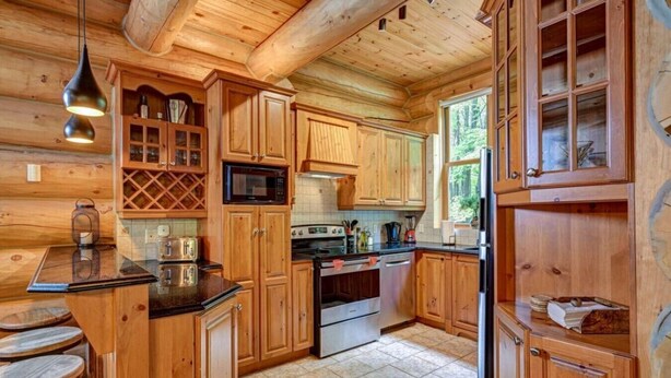 Ein Interieur einer Holzhütte mit einer Küchenzeile, ausgestattet mit Holzschränken, einer Mikrowelle, einem Herd und einem Kühlschrank.
