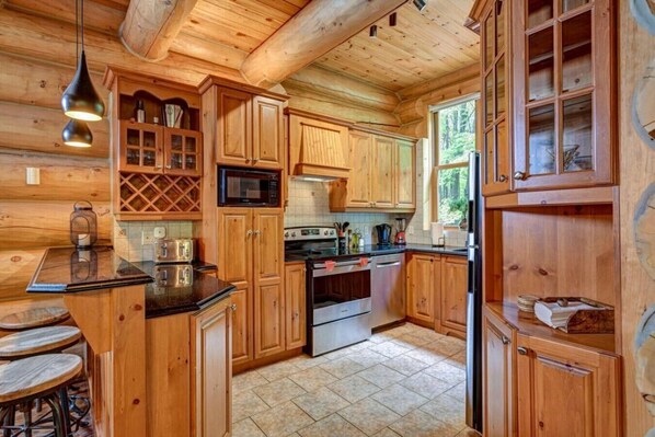 Een houten cabin-interieur met een keukenhoek, voorzien van houten kastjes, een magnetron, een fornuis en een koelkast.