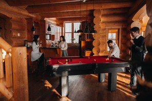 A wooden interior with a pool table, wooden cabinets, and a window. - Private Hot Tub / Sauna / Indoor Pool / Nyctale (Mille-Isles)