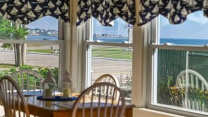 A dining area with a view of a coastal road and a marina. - Long Sands Beach Cottage in York (York)