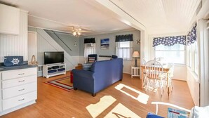 A compact living space with a sofa, TV, and a dining area with chairs. - Long Sands Beach Cottage in York (York)