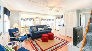A compact living space with a sofa, chairs, a TV, and a ceiling fan. - Long Sands Beach Cottage in York (York)