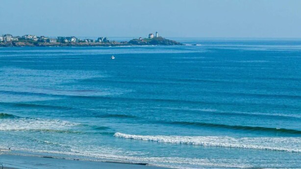 A coastal view with a lighthouse and buildings on a small island. - Long Sands Beach Cottage in York (York)