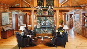 A log cabin interior with a stone fireplace, leather furniture, and wooden walls.