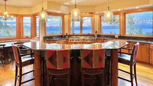 A kitchen with a central island, wooden cabinets, and large windows offering a view of the mountains.