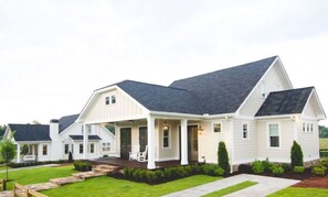 A large, single-story house with a covered porch and a well-maintained lawn. - Kaya Cottages (Cleveland)