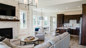 Ein großzügiges Wohnzimmer mit Kamin, einer großen Couch und einem Essbereich mit Tisch und Stühlen.