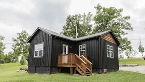 A black wooden cabin with a wooden deck and a staircase leading to the entrance. - Mountain Cabin in Jamestown (Jamestown)