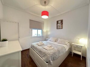 Ein Schlafzimmer mit Bett, Nachttisch, Lampe und einem motivierenden Zitat an der Wand.
