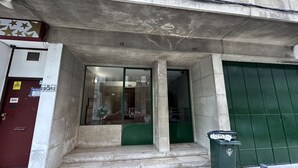 A building entrance with a glass door, a green door, and a trash bin. - Central Lisbon by Trip2Portugal (Lisbon)