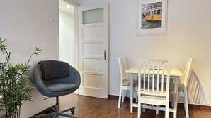 A room with a dining table and chairs, a grey office chair, a potted plant, and a door. - Central Lisbon by Trip2Portugal (Lisbon)