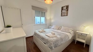 A modern bedroom with a bed, bedside table, and a small desk with a lamp. - Central Lisbon by Trip2Portugal (Lisbon)