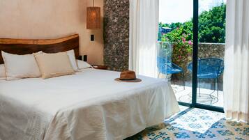 Un dormitorio con cama, pared de piedra, ventana con cortinas y vistas a la vegetación.