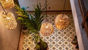 A staircase with wooden railings, potted plants, wicker pendant lights, and patterned tile flooring. - Mero Mero Hotel (El Cuyo)