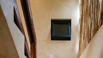 A staircase with wooden handrails and beige carpeted steps leading to a landing with a small table and a framed picture on the wall.