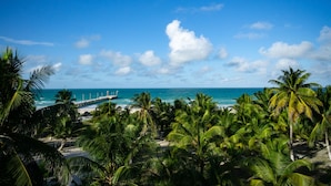 A beach with palm trees, a pier, and the ocean. - Mero Mero Hotel (El Cuyo)